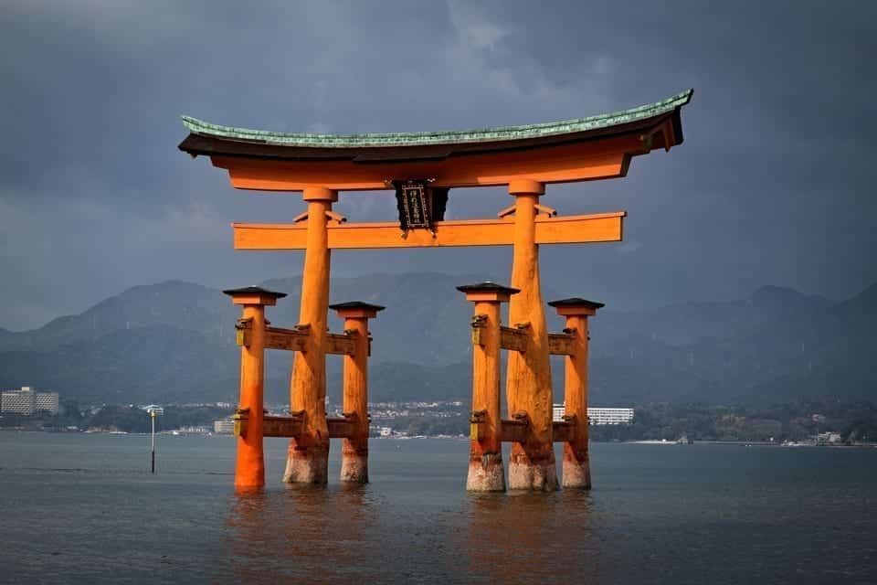 View of floating torii gate of Itskukushima shrine against a dark sky.