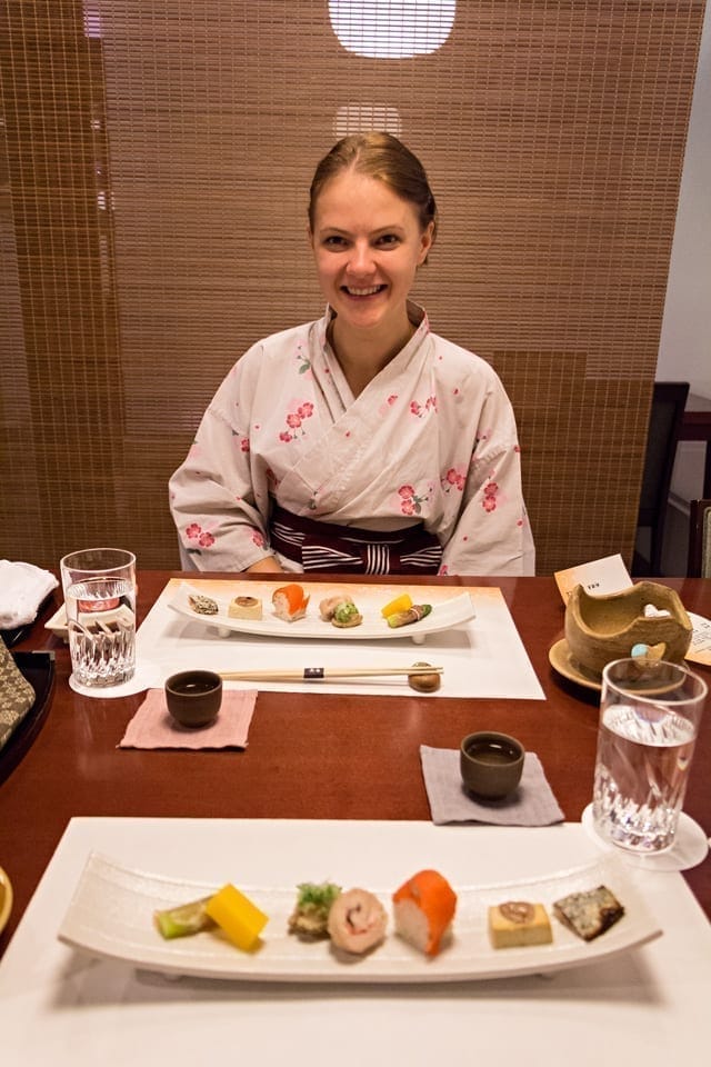 Picture of a young lady dressed in a traditional yukata, enjoying her kaiseki dinner in a ryokan.