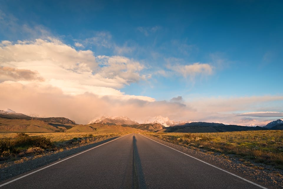 A road near El Chalten in Argentine Patagonia at sunrise with mountains and clouds in the background