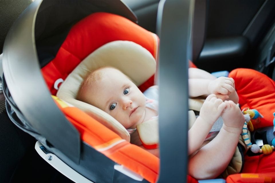 kid in a car seat road trip essentials for kids