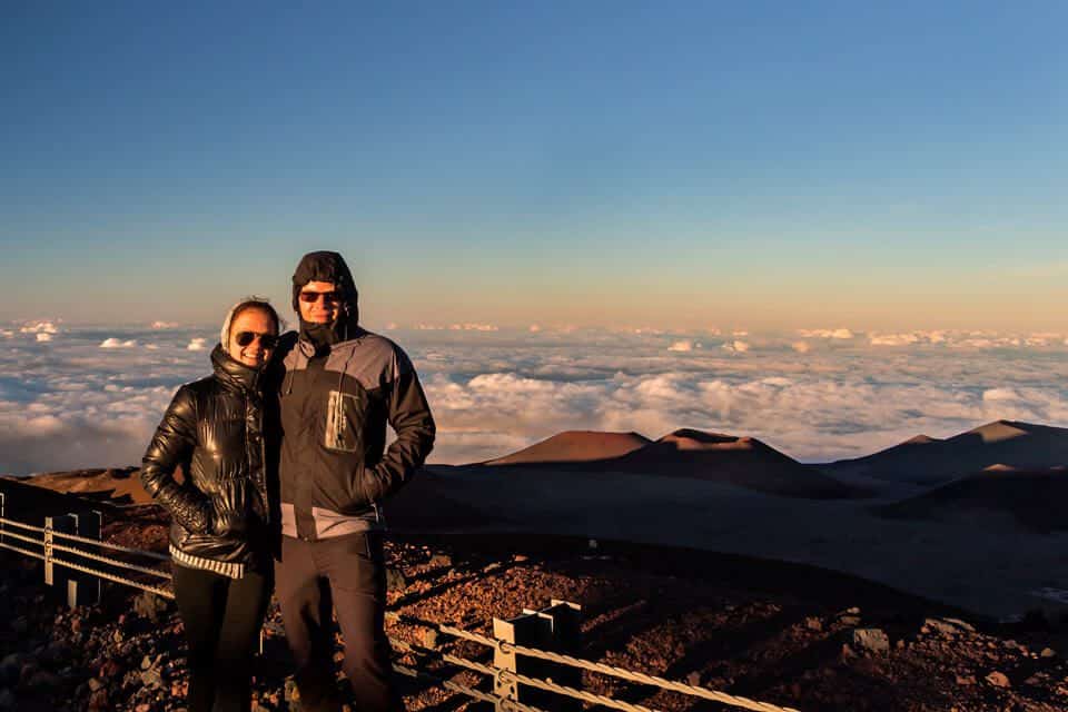 a couple on the summit of Mauna Kea during sunset with cinder cones in the background