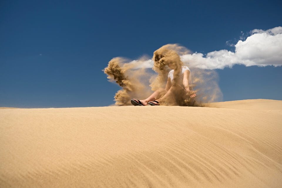 woman getting sand thrown on herself on a dune in Gran Canaria