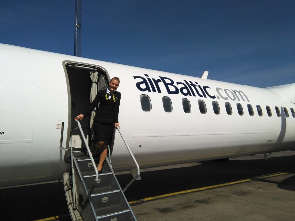 a flight attendant on the stairs of an airplane in the airport