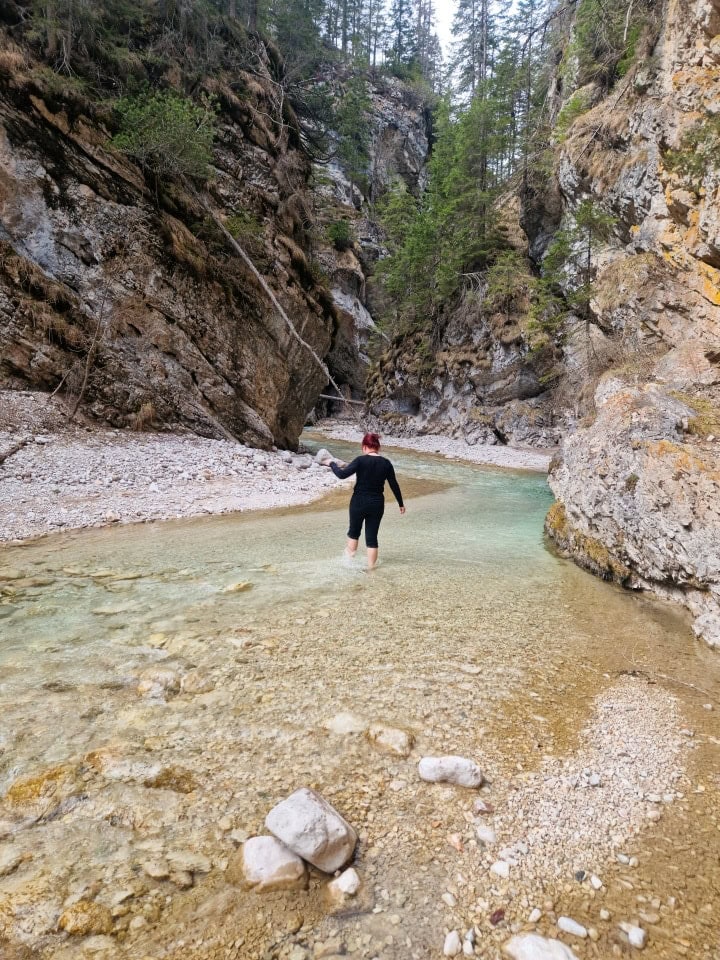 a woman walking in the cold waters of river boite in dolomites italy