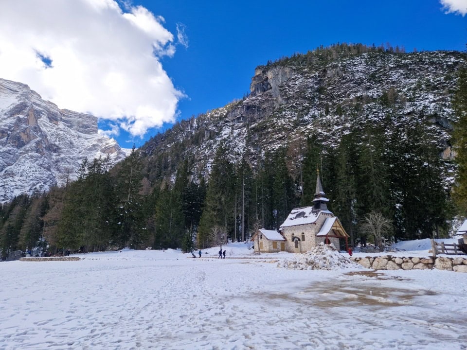 a little cute church, mountains, trees, and snow lago braies dolomites italy