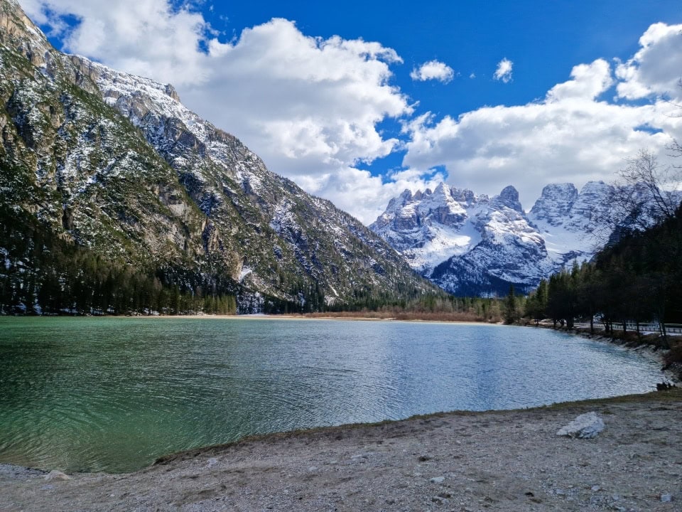 lake landro in a shadow with very snowy mountains in the background - there's still quite a lot of snow in dolomites in april