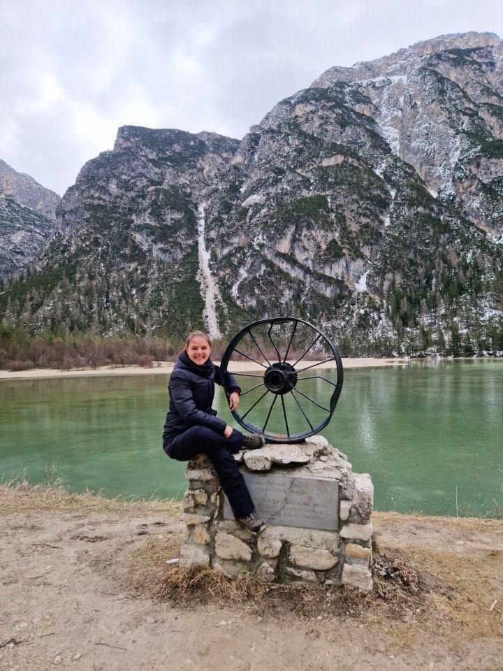 turquoise waters of lake landro, snowy mountains, and me by a wheel in dolomites italy