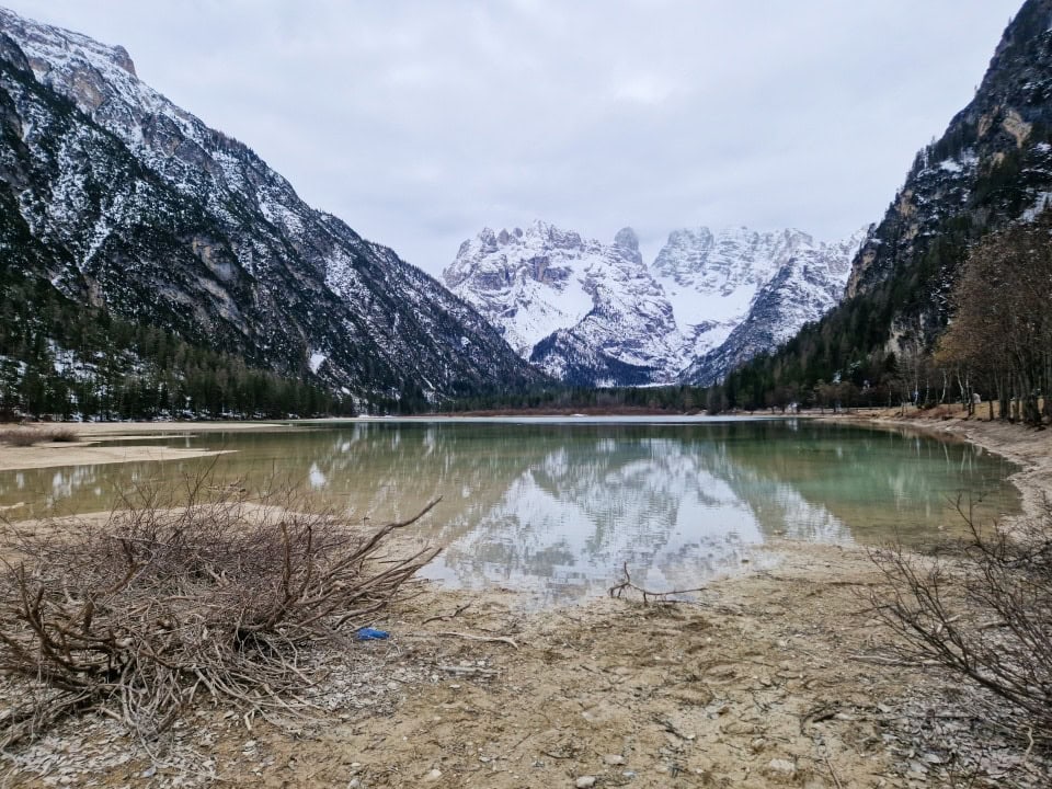 lake landro on a foggy morning with snowy mountains in the background in dolomites italy