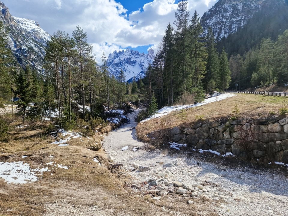 an empty river bed with snowy mountains around it in dolomites italy