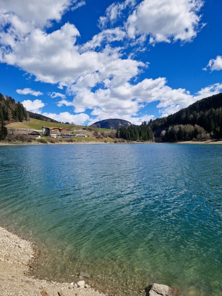 a view of a hotel and turquoise green waters of lake valdaora, dolomites, italy