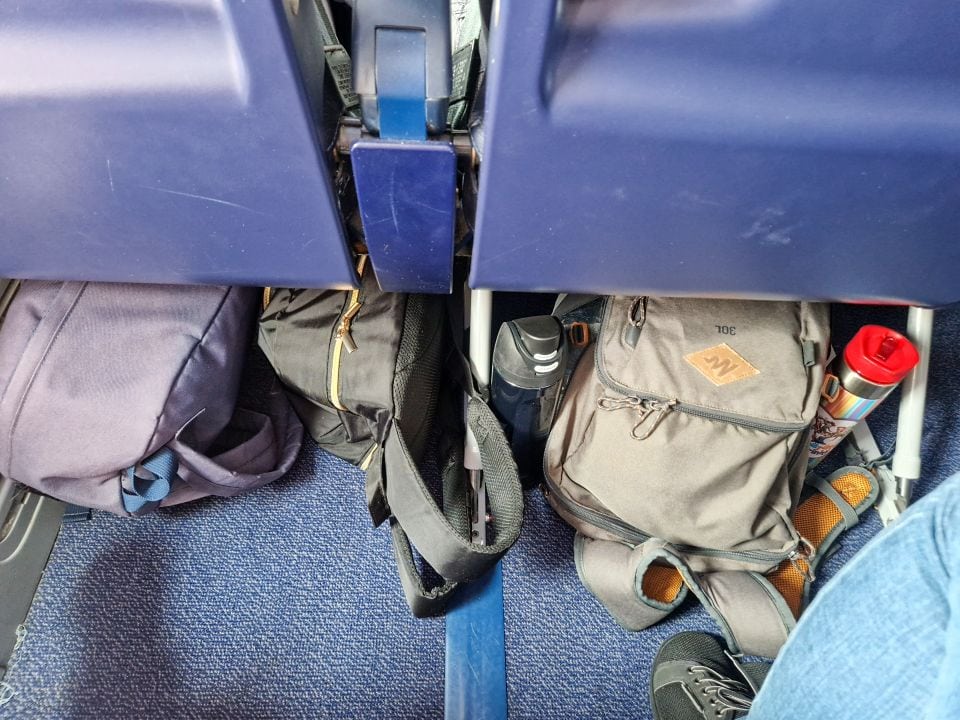 bags under the seat in an airplane with water bottles prepared