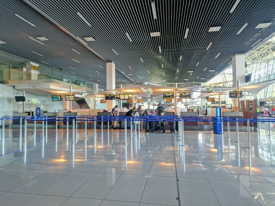 checked luggage area in bratislava airport with blue line dividers and some people waiting to drop off luggage