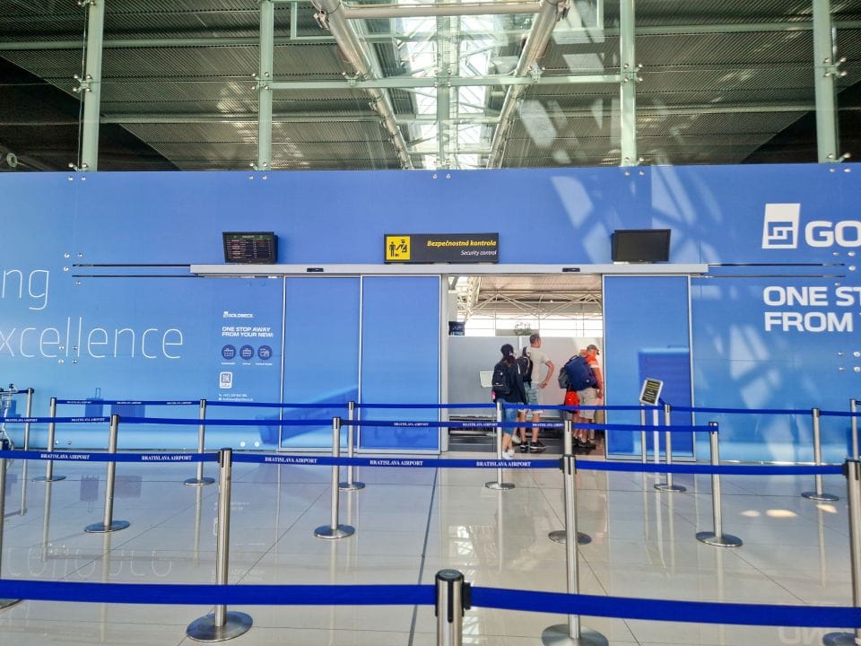 the entrance to the security check area in bratislava airport with a blue wall covering the actual security check